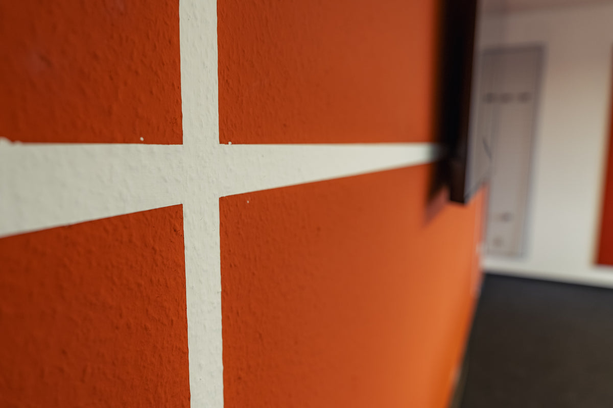 Orangene Wand mit weißen Streifen wie ein Padel Court