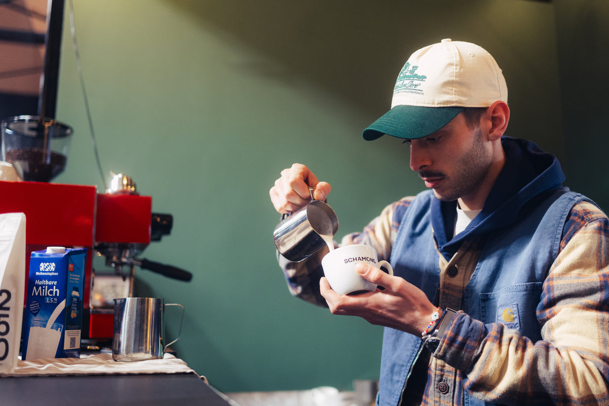 Barista mit Tasse und Milchkanne für Cappuccino